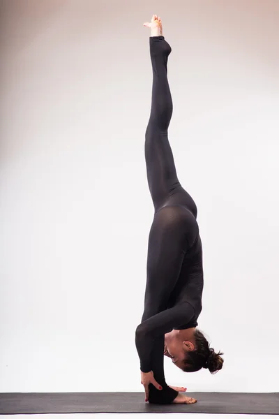 Giovane bella yoga femminile in posa su uno sfondo studio — Foto Stock