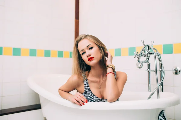 Young caucasian blonde girl lying in white bathroom — Stock Fotó