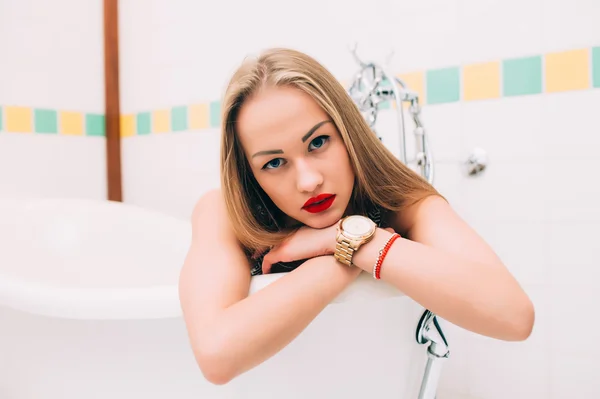 Young caucasian blonde girl lying in white bathroom — Stok fotoğraf