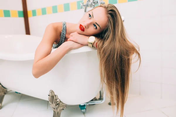 Young caucasian blonde girl lying in white bathroom — Stock Fotó