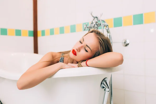 Young caucasian blonde girl lying in white bathroom — ストック写真