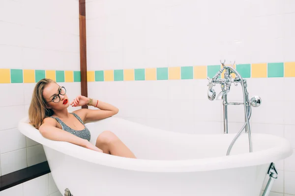 Young caucasian blonde girl lying in white bathroom — Stock Fotó