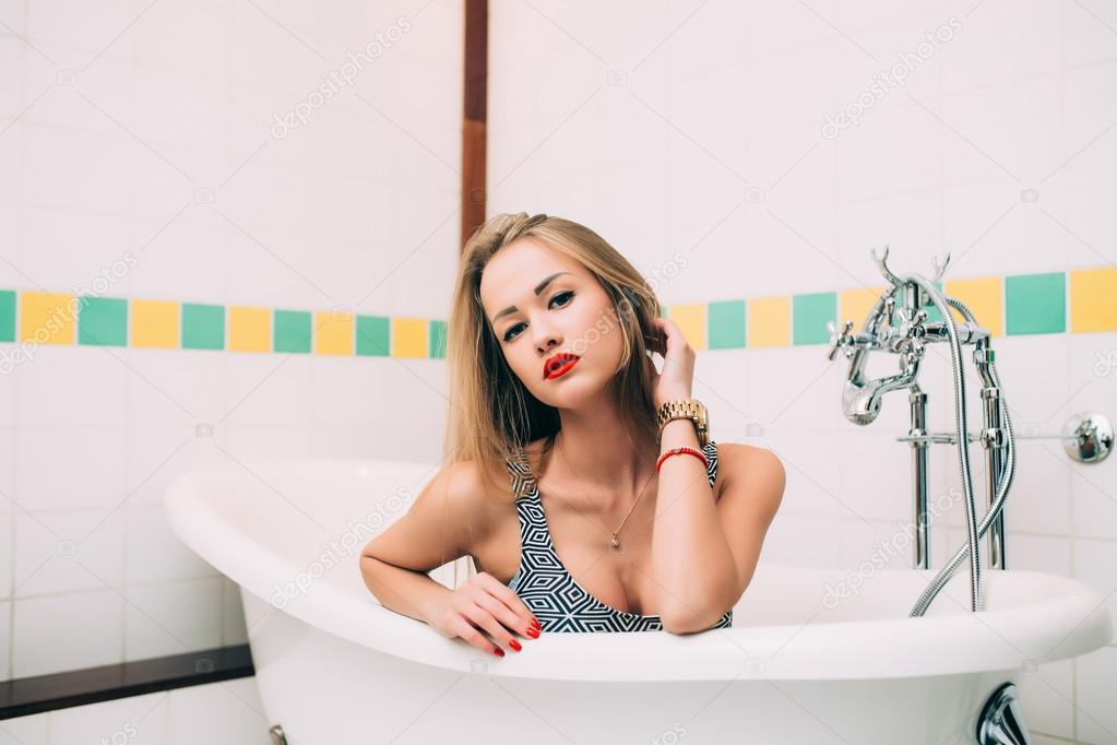 Young caucasian blonde girl lying in white bathroom