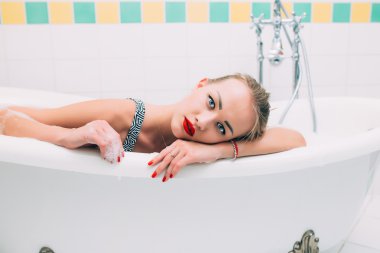 Passionate young caucasian lying in white bathroom