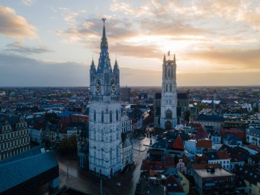 Smooth aerial movement over Ghent old town with towers, canals, and stone architecture.