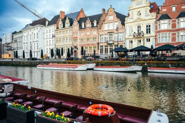 Ghent, Belgium - October 5, 2025 - People walking beside the canal in Ghent surrounded by old Belgian architecture.
