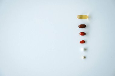 Sağlık, ilaç ve ilaç tedavisini sembolize eden temiz beyaz bir geçmişe yayılmış çeşitli ilaç ve kapsüller.