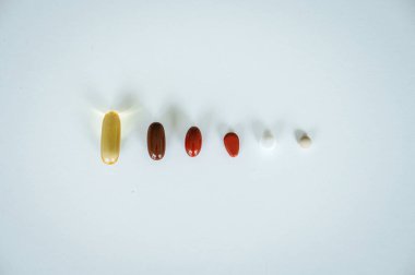 Sağlık, ilaç ve ilaç tedavisini sembolize eden temiz beyaz bir geçmişe yayılmış çeşitli ilaç ve kapsüller.