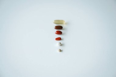 Sağlık, ilaç ve ilaç tedavisini sembolize eden temiz beyaz bir geçmişe yayılmış çeşitli ilaç ve kapsüller.