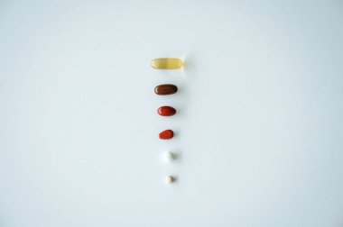 Sağlık, ilaç ve ilaç tedavisini sembolize eden temiz beyaz bir geçmişe yayılmış çeşitli ilaç ve kapsüller.