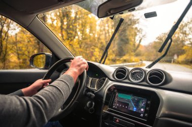 Sürücü koltuğu manzaralı. Direksiyonda el ele tutuşan adam, yakın plan. Ormanda yol