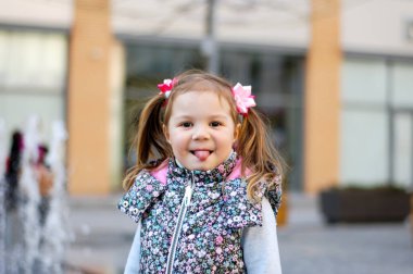 Sevimli Çocuk Mahalle Oyun Bahçesinde Güzel Zamanlar ve Maceralar Geçiriyor. Dilini gösteren sağlıklı, mutlu bir bebek. Çocuklar için şık kıyafetler.