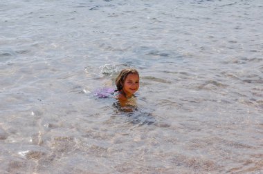 Küçük sevimli kız plajda yazın tadını çıkarıyor. Mutlu, neşeli ve çok tatlı bir kız. Yaz konsepti