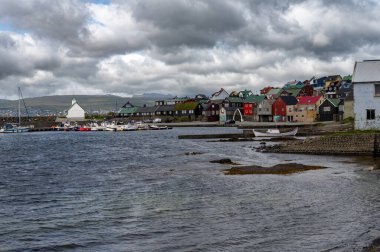 Nolsoy, Faroe Adaları - 5 Ağustos 2025: Nolsoy, Faroe Adaları manzaralı deniz kenarındaki renkli balıkçıların evleri, geleneksel İskandinav cazibesini ve kıyı yaşam tarzını yansıtıyor.