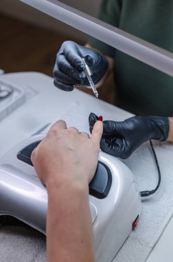 Tırnak bakım araçları ve odaklı eller ile profesyonel manikür prosedürünün ayrıntılı görünümü.