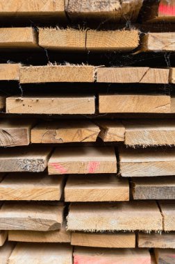 Tahtaların yakın çekim dokusu üst üste istiflenmiş, doğal ahşap tanecikleri, pürüzlü kenarları ve katmanlı inşaat malzemelerini gösteriyor..