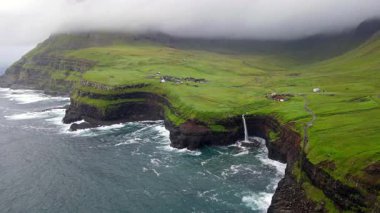 Dramatik Mulafossur şelalesi Gasadalur köyü ve arka planda kayalıklarla okyanusa dökülüyor..