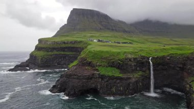 Dramatik Mulafossur şelalesi Gasadalur köyü ve arka planda kayalıklarla okyanusa dökülüyor..