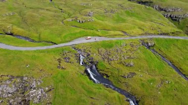 Faroe Adaları 'nın dramatik yeşil uçurumları, kayalık kıyı şeridi ve bulutlu kuzey havası altındaki okyanus dalgalarıyla manzarası. Nordladalur 'un sert ve el değmemiş doğası.