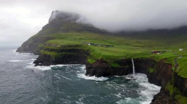 Dramatik Mulafossur şelalesi Gasadalur köyü ve arka planda kayalıklarla okyanusa dökülüyor..