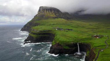 Dramatik Mulafossur şelalesi Gasadalur köyü ve arka planda kayalıklarla okyanusa dökülüyor..