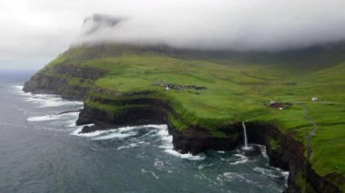 Dramatik Mulafossur şelalesi Gasadalur köyü ve arka planda kayalıklarla okyanusa dökülüyor..