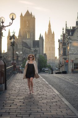 Şık, bakımlı, şık bir kadın bej ceket ve güneş gözlüğü ile şehirde dolanıyor. Kendinden emin ve sofistike görünüyorsun.