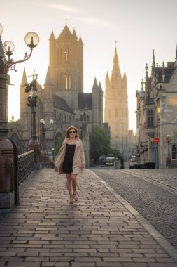 Şık, bakımlı, şık bir kadın bej ceket ve güneş gözlüğü ile şehirde dolanıyor. Kendinden emin ve sofistike görünüyorsun.