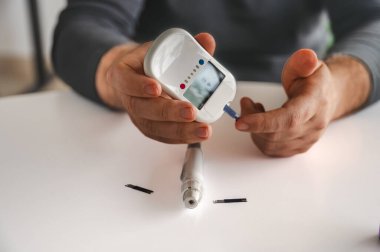 Kan şekeri seviyesini ölçmek için parmağındaki mızrakla bir adamın ellerini yakın plan çekeceğiz. Diyabet bakımı, glisemi izleme ve sağlık yönetimi kavramı.