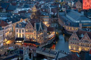 Gent, Belçika - 5 Aralık 2025: Gent Noel Pazarı 'nın bayram ışıkları, samimi tezgahlar ve tarihi şehir merkezinde canlı kalabalıklarla parıldayan hava manzarası.