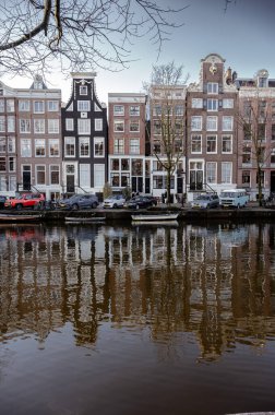 Amsterdam, Hollanda - 3 Ocak 2026: Tarihsel binalar ve botlar, kışın gökyüzü altında sakin kanal sularına yansıdı.