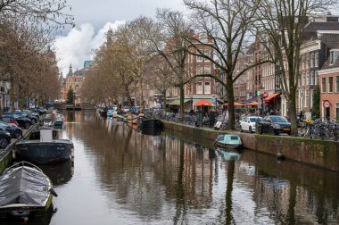 Amsterdam, Hollanda - 3 Ocak 2026: Tarihsel binalar ve botlar, kışın gökyüzü altında sakin kanal sularına yansıdı.