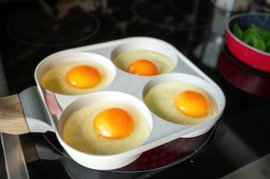 Özel bölünmüş yumurta tavasında pişirilmiş mükemmel kızarmış yumurtalar basit, lezzetli ve görsel olarak çekici bir kahvaltı sahnesi oluşturuyor..