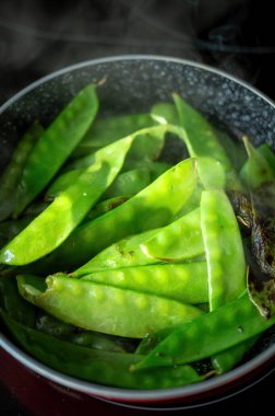 Siyah arka plan üzerine deniz tuzu serpiştirilmiş basit haşlanmış fasulye manzarası. En az sağlıklı gıda konsepti.