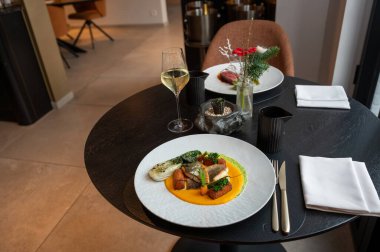 Rafine edilmiş balık ana yemeği, sanatsal kaplama ve altın detaylarla, lüks bir yemek ortamında sunuluyor..