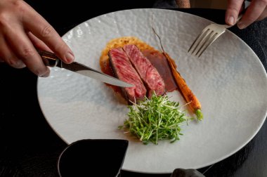 Yumuşak çizgili biftek, renkli ve sulu desenli, koyu bir arka planda sergileniyor..