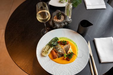 Şatafatlı bir restoranda servis edilen dekoratif altın garnitürlü gurme balık yemeğinin yakın görüntüsü..