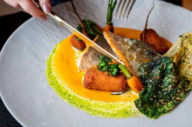 Üst düzey bir yemek ortamında servis edilen altın garnitürlü güzel bir balık tabağının yakın çekimi..