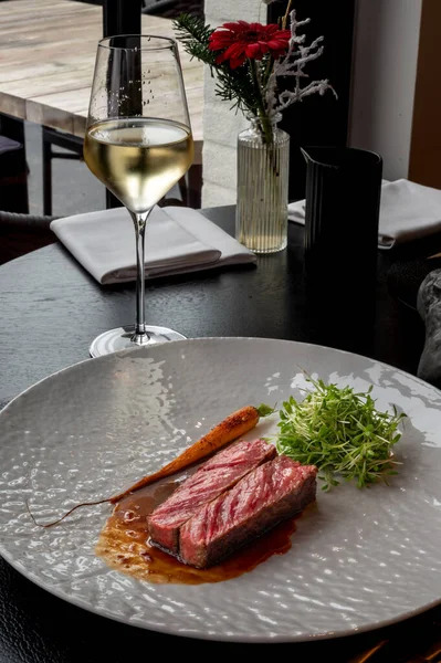 Mükemmel kavrulmuş dış görünüşlü sulu çizgili biftek, gurme sunumu için karanlık bir yüzey üzerinde servis edilir..