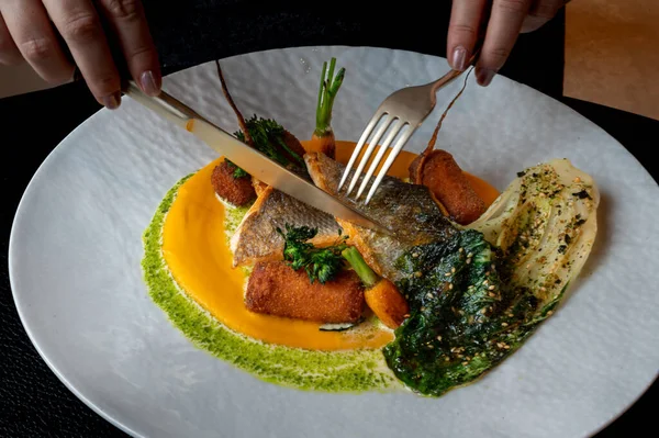 Pahalı bir restoranda, sanatsal kaplama ve altın garnitürle sunulan zarif balık tabağı..