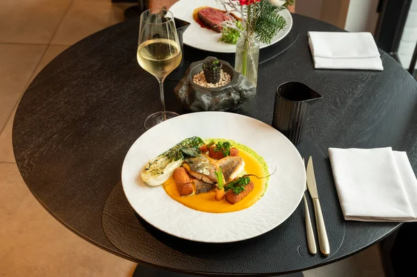 Şatafatlı bir yemek alanında rafine edilmiş garnitürlü bir gurme balık yemeğinin sofistike sunumu..