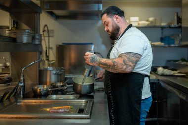 Yakışıklı şef, profesyonel bir restoranda yemek pişirmeye odaklanıyor..