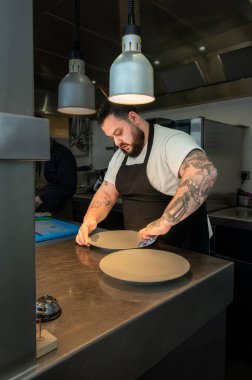 Yakışıklı şef profesyonel bir mutfak ortamında gurme yemeği hazırlamaya odaklanmış..