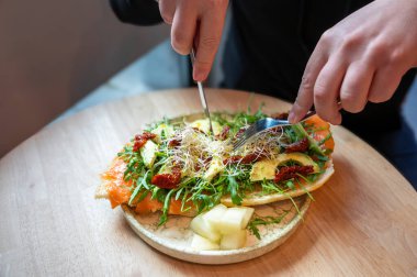 Somon, avokado yağı, marul ve domates salatasıyla kaplı kızarmış bruschetta..