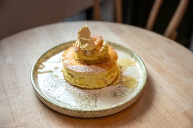 Yumuşak tereyağı ile servis edilen sıcak, tüylü pasta yavaşça eriyor ve ballı şelale tepesine dökülüyor.