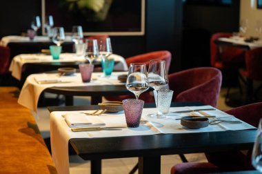 Renkli cam eşyalar, şarap bardakları, düzgünce katlanmış peçeteler ve çubukla hazırlanmış samimi etkinlik masaları.