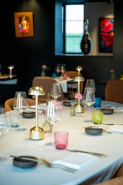 Güneşli restoran köşesi masa ve pencere ışığı, cam yansımaları, lamba ve çerçeveli sanat