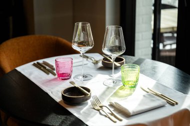 Şarap kadehleri, renkli bardaklar, altın çatal bıçak takımı, beyaz çarşaf, gün ışığı...