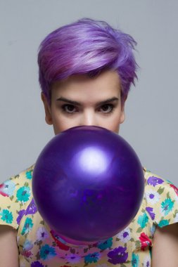 Bir balon ile ağzını tutan Menekşe kısa saçlı kadın