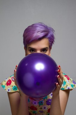 Bir balon ile iki ellerini tutarak Menekşe kısa saçlı girll